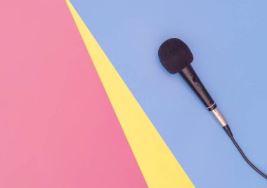 Müzik konsepti için mavi pembe sarı arka plan üzerinde siyah mikrofon