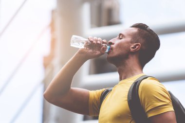 Sarı sportif adam sıcak gün açık su içiyor