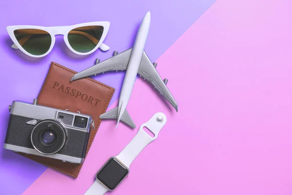 Travel accessories objects and gadgets top view flatlay on purple and pink