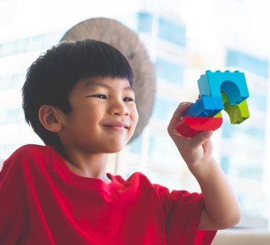 Oyuncak blokları eğitim için oturma odasına yığan mutlu çocuk.