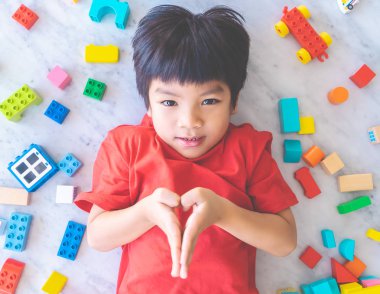 Etrafı renkli oyuncak bloklarıyla çevrili mutlu çocuk..