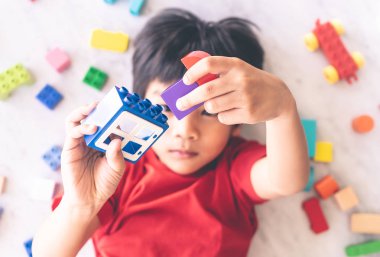 Etrafı renkli oyuncak bloklarıyla çevrili mutlu çocuk..