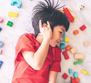 Etrafı renkli oyuncak bloklarıyla çevrili mutlu çocuk..