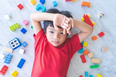 Etrafı renkli oyuncak bloklarıyla çevrili mutlu çocuk..