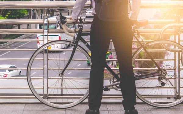 Business man stading with bike on a city traffic