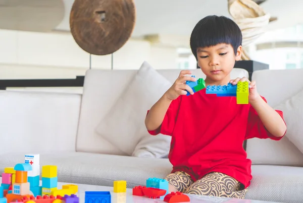 Asian boy stacking Toy blocks on a living room table