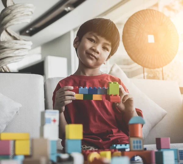 Ásia menino empilhamento brinquedo blocos no um sala de estar mesa — Fotografia de Stock