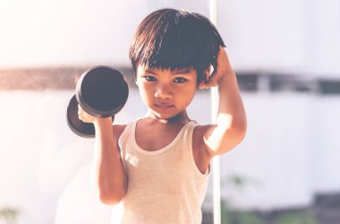 Küçük çocuk pencere şehrinin yanında dambılla çalışıyor..