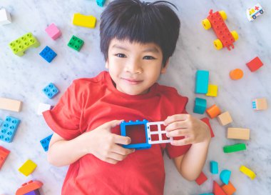 Etrafı renkli oyuncak bloklarıyla çevrili mutlu çocuk..