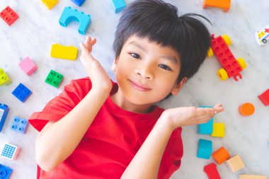 Etrafı renkli oyuncak bloklarıyla çevrili mutlu çocuk..