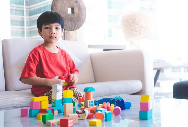 Happy boy stacking Toy blocks on a living room for educational t