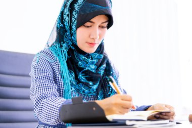 Müslüman kadın ofis masasında dijital tablet kullanıyor