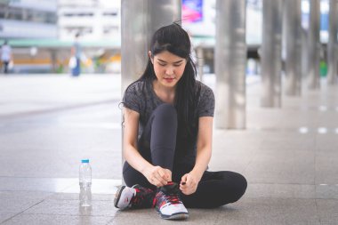 Sportif kadın şehir koşusu için ayakkabılarını bağlıyor