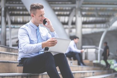 İş adamı açık havada oturan cep telefonu kullanıyor