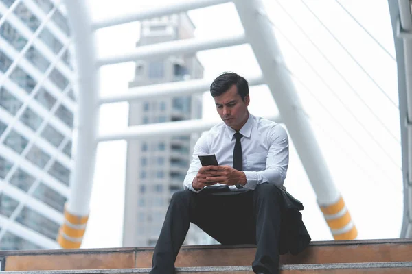 Homme d'affaires utilise téléphone portable assis en plein air — Photo