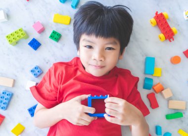 Etrafı renkli oyuncak bloklarıyla çevrili mutlu çocuk..