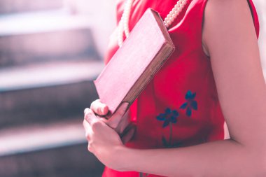 Elinde kırmızı bir kitap tutan Kızıl Asyalı kadın