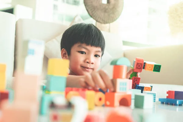 Happy boy stacking Toy blocks on a living room for educational t