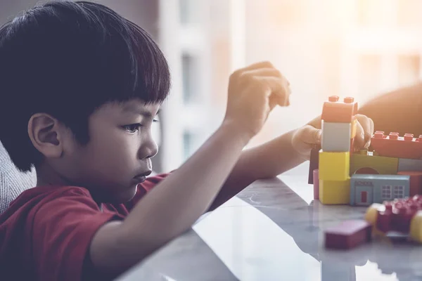 Asian boy stacking Toy blocks on a living room table
