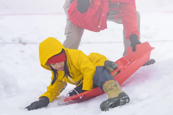 Vader helpt haar dochter met de sneeuwslee. — Stockfoto