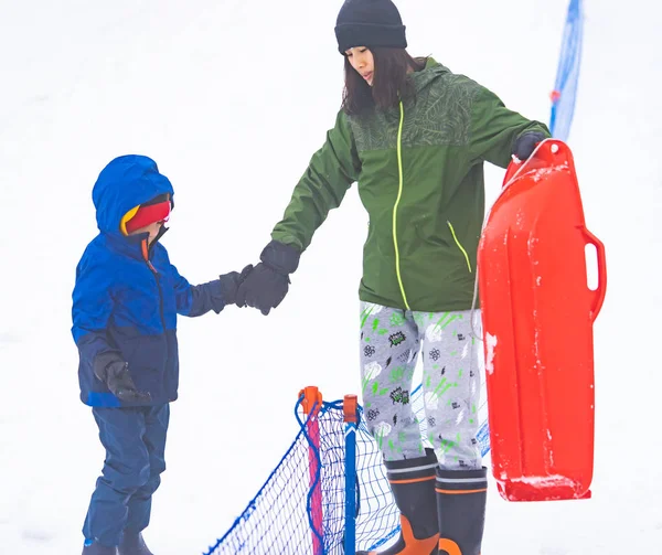 Mother is helping her boy to ride the sled — Stock Photo, Image