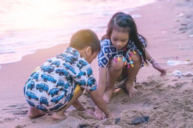 İki kardeş çocuk Pattaya B 'de kum ve el sallıyor.