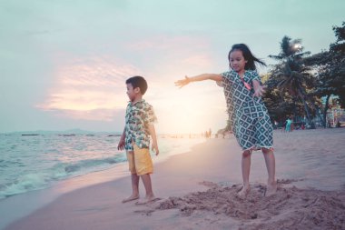 İki kardeş çocuk Pattaya B 'de kum ve el sallıyor.
