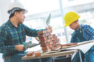 Küçük çocuk kendi yorumundan tuğla duvar örmeyi öğreniyor.