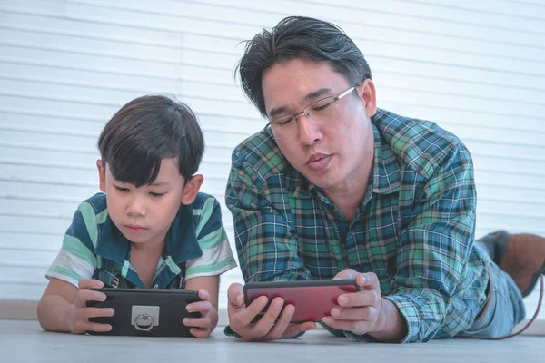 Asian Father is teaching his son to use the smartphone and inter