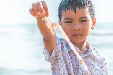 Çocuklar sahilde bulduğu plastik saman tutuyor.