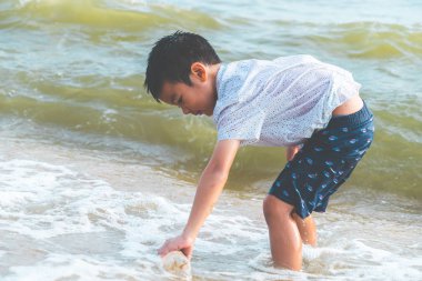 Çocuklar beac üzerinde bulduğu plastik şişeyi temizliyor.