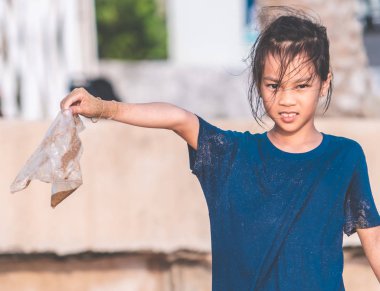 Çocuklar sahilde bulduğu plastik poşeti tutuyor.