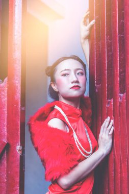 Utangaç Çinli kadın kırmızı ahşap kapının arkasında saklanıyor