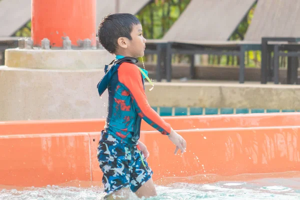 Asyalı çocuk aqua su parkında bir su kaydırağı yanında oynuyor