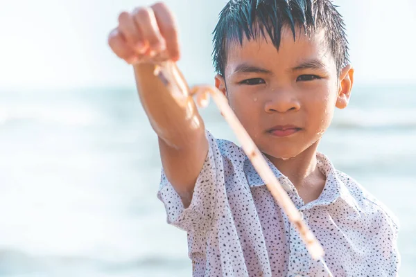 Çocuklar sahilde bulduğu plastik saman tutuyor.