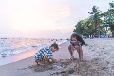 İki kardeş çocuk Pattaya B 'de kum ve el sallıyor.