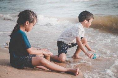 Çocuklar çevresel kirlilik için sahildeki çöpleri temizliyor.