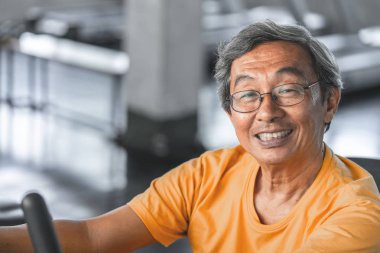 Mutlu Kıdemli erkek o yaşlı için fitness makinesi üzerinde çalışıyor