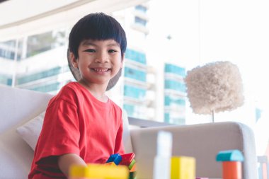 Oyuncak blokları eğitim için oturma odasına yığan mutlu çocuk.