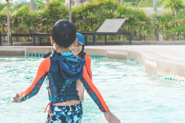 Two Asian siblings in playing together in Water Aqua park pool.