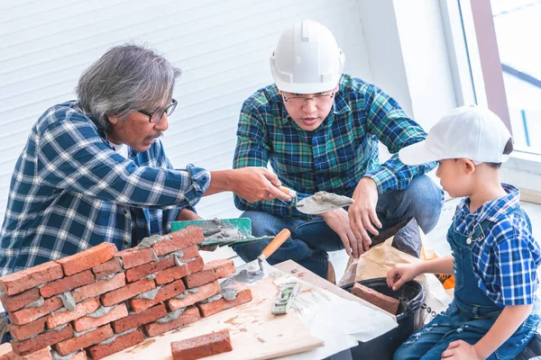 Tre generationens byggare hjälper till att bygga tegelvägg för — Stockfoto