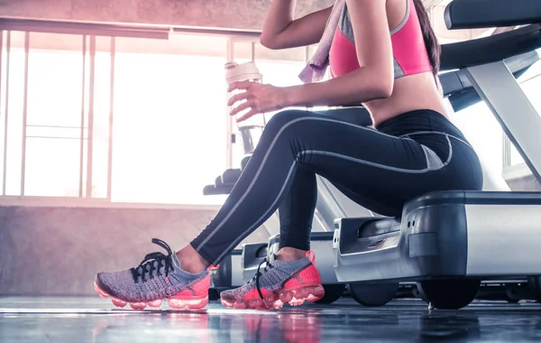 Mujer está bebiendo agua en el entrenamiento de la cinta de correr en gimnasio gimnasio unre — Foto de Stock