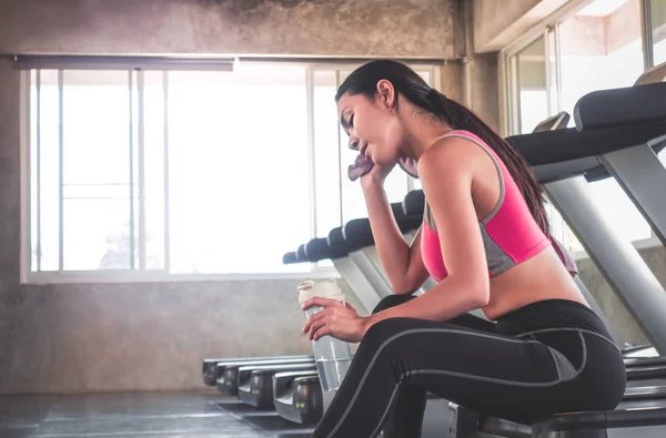 La mujer está bebiendo agua en el entrenamiento de la cinta de correr en el gimnasio — Foto de Stock