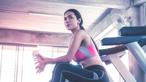 La mujer está bebiendo agua en el entrenamiento de la cinta de correr en el gimnasio — Foto de Stock