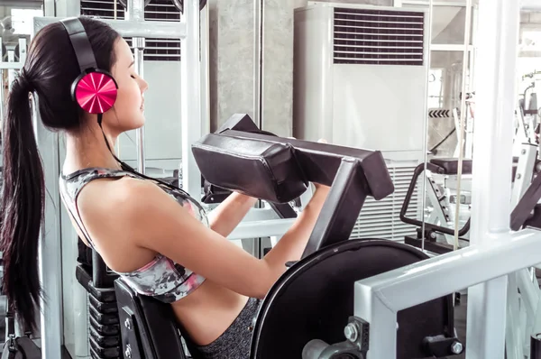 Mujer con auriculares rosados está haciendo ejercicio Abs en la máquina de fitness — Foto de Stock
