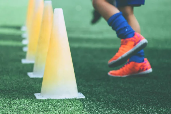 Kinderfüße mit Fußballschuhen trainieren auf Trainingskegel auf Socken — Stockfoto