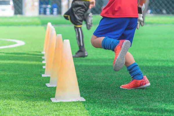 Children feet with soccer boots training on training cone on soc