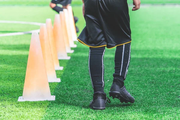 Children feet with soccer boots training on training cone on soc