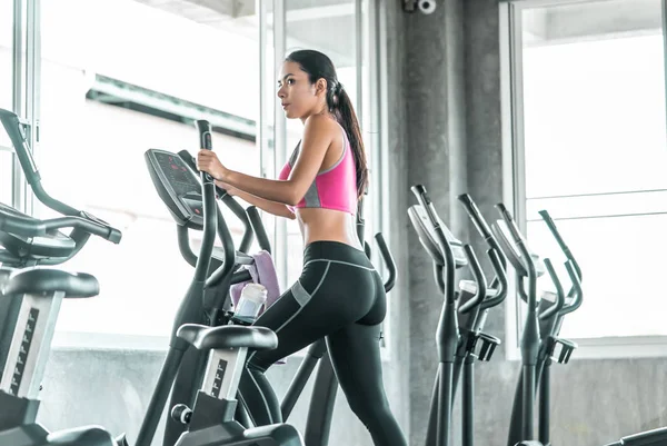 Mujer está trabajando en la máquina escaladora Step en el gimnasio de fitness para — Foto de Stock