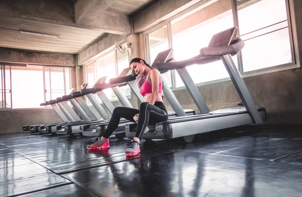 La mujer está bebiendo agua en el entrenamiento de la cinta de correr en el gimnasio — Foto de Stock